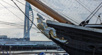 Sideview of the figurehead for HMS Warrior. The figurehead is white with gold details, depicting a bearded male figure with helmet, sword and shield